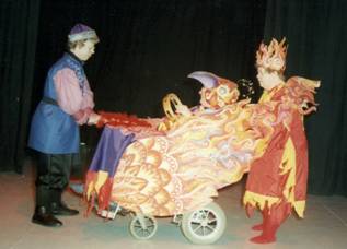 The  fire bird - a wheelchair user and pusher in bright red and yellow costumes giving Prince Ivan a golden feather to unlock the bewitched forest